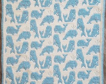May include: A crocheted baby blanket with a blue and white whale pattern. The blanket is made with a soft yarn and is perfect for a baby shower gift.