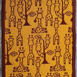 May include: A crocheted rug featuring a pattern of giraffes in a yellow and brown colour scheme.