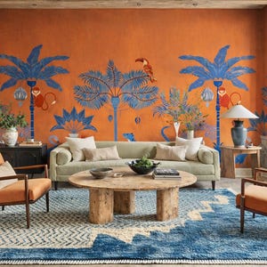 Peut inclure: Un salon avec un mur orange orné de peintures murales de palmiers bleus, un canapé vert et une table basse en bois. Deux chaises oranges et un tapis à motifs bleus et blancs complètent le décor. Une grande fenêtre laisse entrer la lumière naturelle.