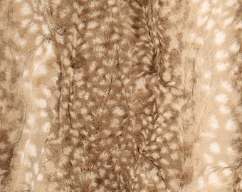May include: Close-up of a soft, plush fabric with a brown and white spotted pattern. The fabric has a fuzzy texture and a subtle sheen.