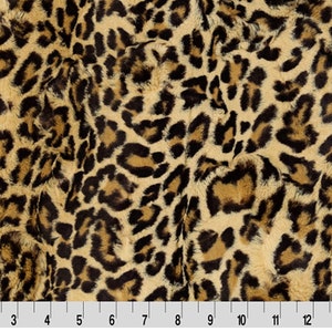 May include: A close-up of a brown and black leopard print fabric. The fabric has a soft, fuzzy texture.