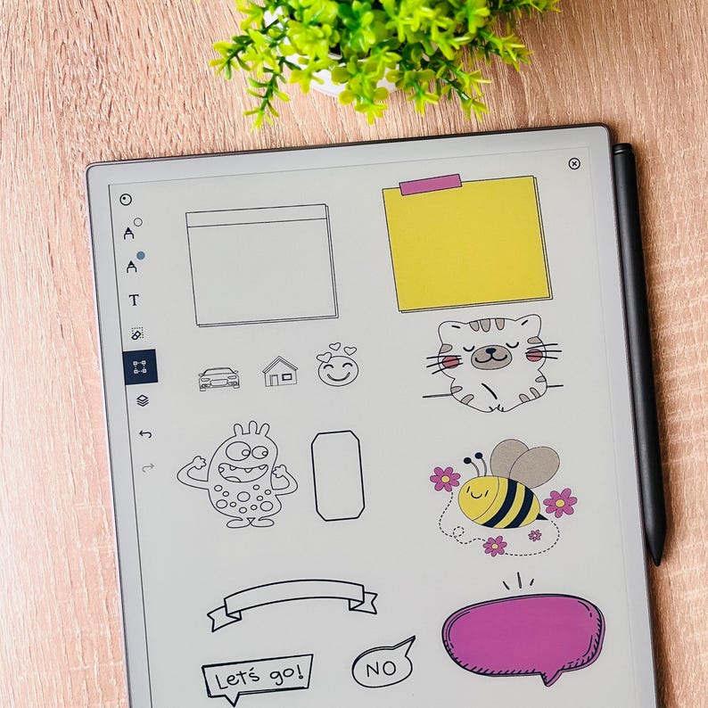 以下が含まれることがあります： デジタルステッカーと描画ツールが表示されたデジタルタブレット。ステッカーには、猫、蜂、モンスター、吹き出し、バナーが含まれます。黒いスタイラスがタブレットの右側にあります。「Let's go!」と「NO」の文字も表示されています。