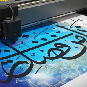 K&ouml;nnte beinhalten: Ein Gro&szlig;formatdrucker in Betrieb, der ein Poster mit arabischer Kalligraphie druckt. Das Kunstwerk zeigt schwarze Schrift auf einem blau-wei&szlig;en Hintergrund mit einem Himmelsdesign. Der Druckkopf bewegt sich und tr&auml;gt Tinte auf das Papier auf.
