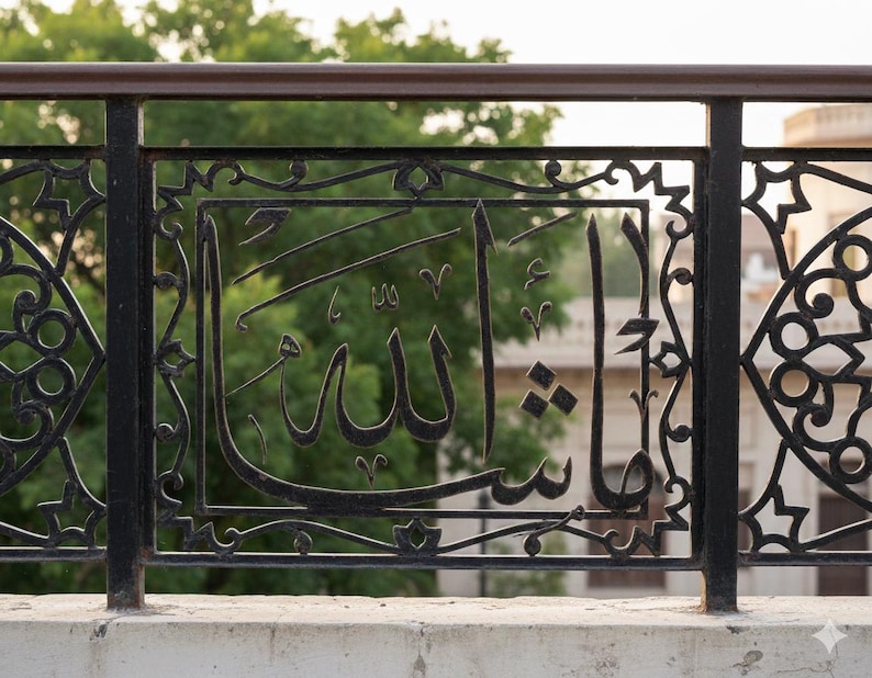 K&ouml;nnte beinhalten: Schwarzes schmiedeeisernes Gel&auml;nder mit arabischer Kalligraphie. Das Design zeigt verzierte geometrische Muster und das Wort "Allah" in eleganter Schrift. Der Hintergrund zeigt gr&uuml;nes Laub und ein Geb&auml;ude.