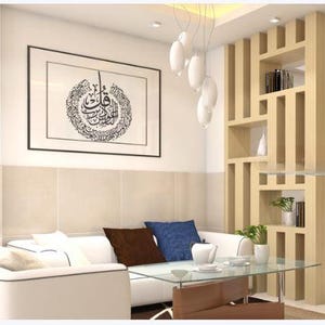 K&ouml;nnte beinhalten: Modernes Wohnzimmer mit wei&szlig;em Sofa, Glastisch und Raumteiler aus Holz. Ein gerahmtes Kunstwerk mit arabischer Kalligraphie h&auml;ngt an der Wand. Blaue und braune Kissen sorgen f&uuml;r Farbe.
