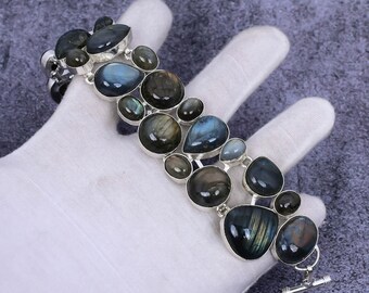 May include: A silver bracelet with a row of iridescent labradorite gemstones. The stones are various shapes and sizes, with a teardrop shape being the most prominent.