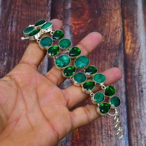 May include: A silver bracelet with a row of green gemstone beads. The bracelet is made of sterling silver and features a clasp closure.