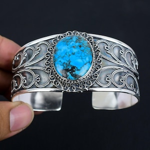 Peut inclure: Un bracelet manchette en argent avec une grande pierre turquoise sertie dans un motif de filigrane.