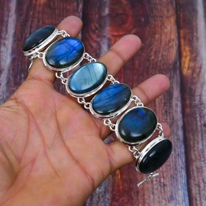 Könnte beinhalten: Ein silbernes Armband mit ovalen Labradorit-Edelsteinen. Das Armband hat einen Knebelverschluss.
