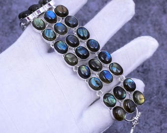 May include: A silver bracelet with multiple rows of oval-shaped labradorite gemstones. The stones have a dark blue and green iridescent sheen.