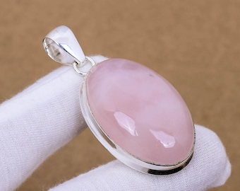 May include: A silver pendant featuring a large oval-shaped pink rose quartz gemstone. The pendant is set in a silver bezel and has a bail for attaching a chain.
