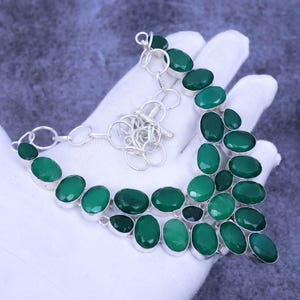 Peut inclure: Un collier en argent avec un pendentif en pierre précieuse verte. Le pendentif est composé de plusieurs pierres de forme ovale.