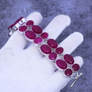 May include: A silver bracelet with a double row of oval-shaped pink gemstones. The bracelet has a toggle clasp.