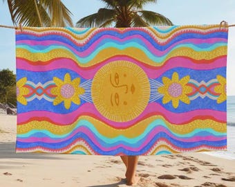 Könnte beinhalten: Ein farbenfrohes Strandtuch mit einem wellenförmigen Muster in den Farben Pink, Blau, Gelb und Orange. In der Mitte des Tuches befindet sich eine stilisierte Sonne mit einem Gesicht und zwei Sonnenblumen auf jeder Seite.