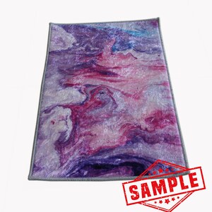 May include: Purple, pink, and white abstract marbled area rug with a gray border. The rug has a modern, contemporary design.