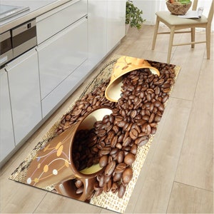 May include: A brown and beige kitchen rug with a design of coffee beans and two overturned coffee mugs. The mugs are decorated with brown and white swirls.