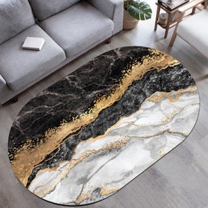 May include: Oval shaped rug with a black, white, and gold marble design. The rug has a modern abstract pattern.