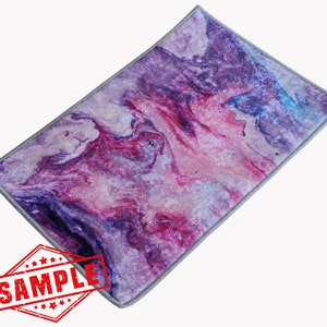 May include: Purple, pink, and blue abstract marbled area rug with a gray border. The rug has a soft, velvety texture.