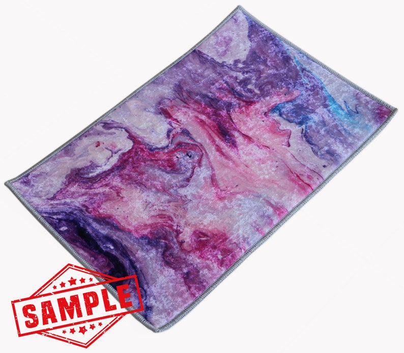May include: Purple, pink, and blue abstract marbled area rug with a gray border. The rug has a soft, velvety texture.