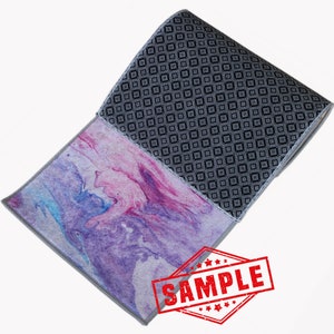 May include: A rolled up runner rug with a geometric pattern on one side and a pink and purple marbled pattern on the other side. The rug has a gray border and the word "SAMPLE" is stamped in red on the rug.
