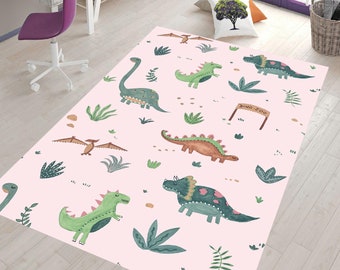 May include: A pink rug with a dinosaur theme. The rug features green, brown, and blue dinosaurs with green leaves and a sign that says "Dino Zoo".