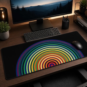 May include: A black desk mouse pad with a colorful rainbow design. The rainbow is composed of concentric semi-circles in shades of red, orange, yellow, green, blue, and purple. A computer mouse and keyboard are also visible.
