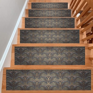 May include: A set of five non-slip stair treads featuring a repeating pattern of gold and blue stylised leaves on a dark background. The treads are designed to add a decorative touch to stairs and provide extra grip.