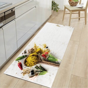 Può includere: Un tappeto da cucina bianco con un design di spezie, erbe e un cucchiaio di legno con polvere gialla. Il tappeto è su un pavimento di legno.