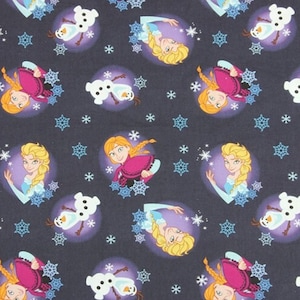 May include: Dark blue fabric featuring repeating patterns of cartoon characters, snowflakes, and snowmen. The characters include a blonde woman in a blue dress and a woman with auburn hair in a pink dress. The snowman is white.