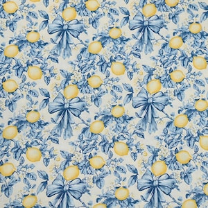 Può includere: Un motivo ripetuto con limoni gialli, fiocchi blu e fogliame blu su sfondo crema. Il design ha un'atmosfera vintage e botanica, con i limoni e i fiocchi distribuiti uniformemente sul tessuto.