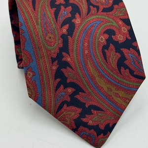 Könnte beinhalten: Gemusterte Krawatte mit Paisley-Design in Rot, Grün, Blau und Gold auf marineblauem Hintergrund. Die Krawatte ist aus glattem Stoff gefertigt und für formelle oder geschäftliche Anlässe geeignet.