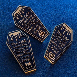 May include: Three black and gold enamel pins shaped like coffins with the text "The DM Killed My Character All I Got Was This Lousy Badge" and a different icon on each pin.