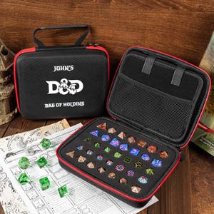Può includere: Custodia con cerniera nera e rossa con la scritta "John's D&D Bag of Holding". La custodia è aperta, rivelando un inserto in schiuma con vari dadi poliedrici colorati. Dadi aggiuntivi sono sparsi su una mappa di gioco.