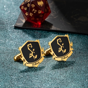 Puede incluir: Gemelos de oro con un diseño de escudo negro que presenta una planta estilizada y el nombre "Clifford" grabado en cada gemelo.