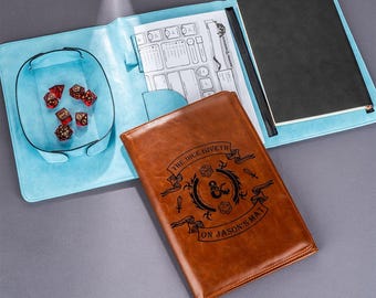 May include: A brown leather notebook with a blue and white cover. The notebook has a dice symbol and the text "The Dice Giveth On Jason's Matt".