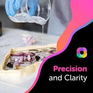 May include: A clear resin is being poured over a tray of pressed flowers and leaves. The resin is clear and viscous, and the flowers are a variety of colors, including pink, purple, and white. The text "Precision and Clarity" is visible in the lower right corner of the image.