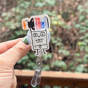 May include: A clear badge reel featuring a cartoon character holding a medication vial. The vial is labeled "Midazolam injection, USP" with dosage information. The reel has a clear plastic clip and a retractable cord.