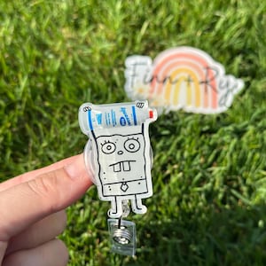Puede incluir: Un portagafete de pl&aacute;stico transparente con un personaje de dibujos animados que sostiene una botella de desinfectante para manos. El personaje est&aacute; dibujado en blanco y negro y tiene una gran sonrisa. El portagafete tiene un cord&oacute;n retr&aacute;ctil.