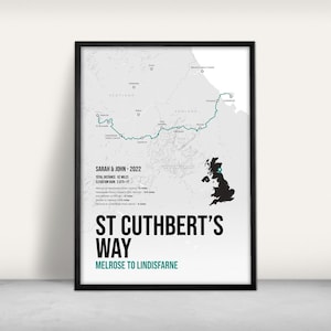 May include: A framed map print of St Cuthbert's Way, a 62-mile trail from Melrose to Lindisfarne. The map features a teal route line across Scotland and England, with text indicating the trail's name and the names of the people who took the trail in 2022.