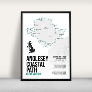 May include: A framed print showing the Anglesey Coastal Path on the Isle of Anglesey. The teal outline of the path is visible, along with black text that reads "Anglesey Coastal Path" and "Sarah & John - 2022". The total distance is 209 km.