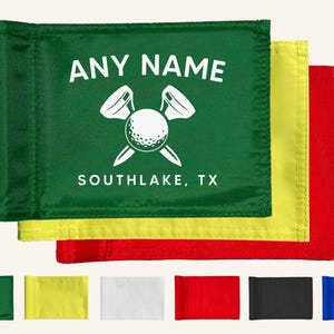 May include: Green golf flag with white text reading "ANY NAME" above a golf ball and tee graphic, and "SOUTHLAKE, TX" below. Additional flags in yellow and red are visible. A row of smaller flags in various colors is at the bottom.