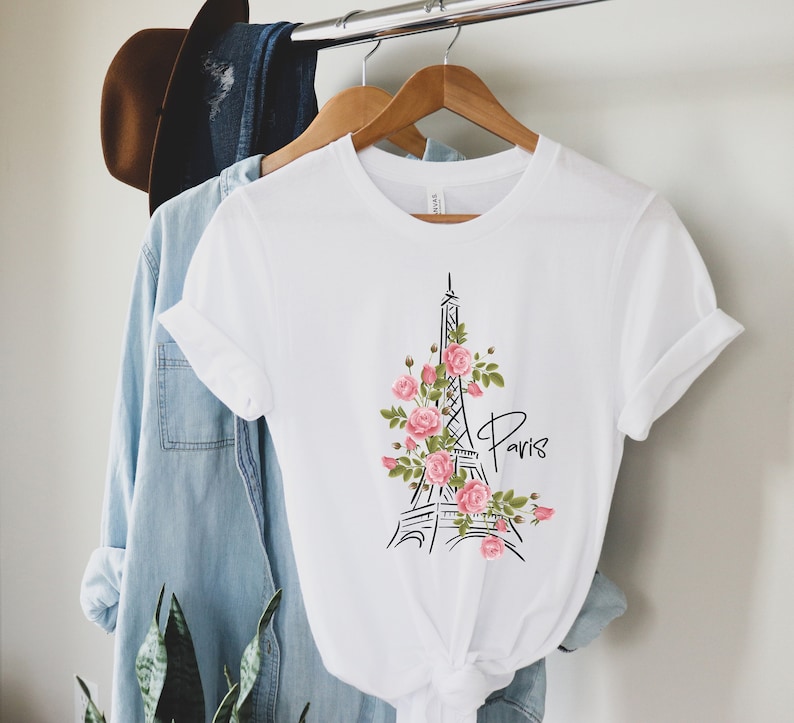 May include: White t-shirt with a black and white illustration of the Eiffel Tower with pink roses and the word "Paris" printed on the front.