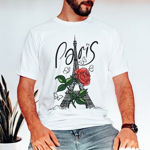May include: White t-shirt with a black and white illustration of the Eiffel Tower, a red rose, and butterflies. The word "Paris" is written in cursive above the tower.