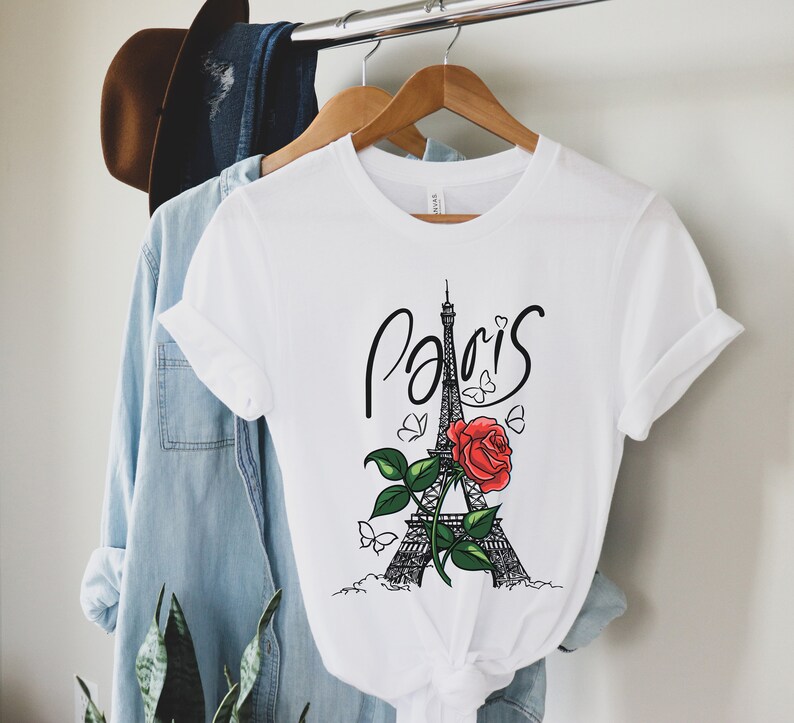 May include: White t-shirt with a black and white illustration of the Eiffel Tower with a red rose and butterflies. The text "Paris" is written in black cursive above the tower.