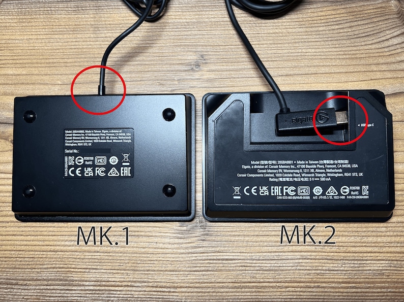 May include: Two black rectangular electronic devices labeled MK.1 and MK.2. The MK.1 has a fixed cable connection, while the MK.2 features a detachable USB-C cable with an Elgato logo. Both units display regulatory markings and model information.