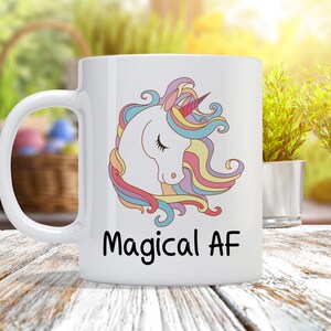 May include: White ceramic mug with a colorful unicorn illustration and the text "Magical AF" printed on it.