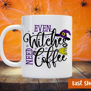 Könnte beinhalten: Eine weiße Keramik-Kaffeetasse mit einem schwarzen und violetten Design, auf dem "Even Witches Need Coffee" steht. Ein Hexenhut und ein Besen sind Teil des Designs. Die Tasse steht auf einer Holzoberfläche mit einem Spinnennetz-Hintergrund.