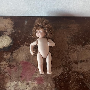 May include: A white ceramic mug with a black handle and the text "But First, Coffee" in a black, handwritten-style font. The mug is on a white surface.