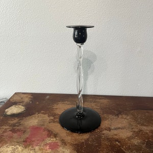 May include: A black glass candlestick with a twisted clear glass stem and a black base.