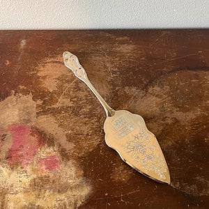 May include: Silver cake server with an ornate design and the words "Merry Christmas" engraved on the blade.